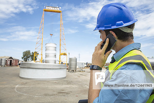 Man in workwear on construction site talking on cell phone