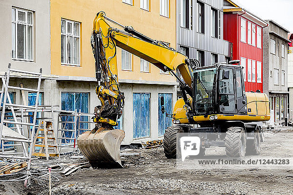 Ein Bagger mit schwerem Gerät steht vor farbenfrohen Gebäuden in der Innenstadt von Reykjavik  ein Zeichen für die boomende Bauindustrie in der Stadt  Reykjavik  Island