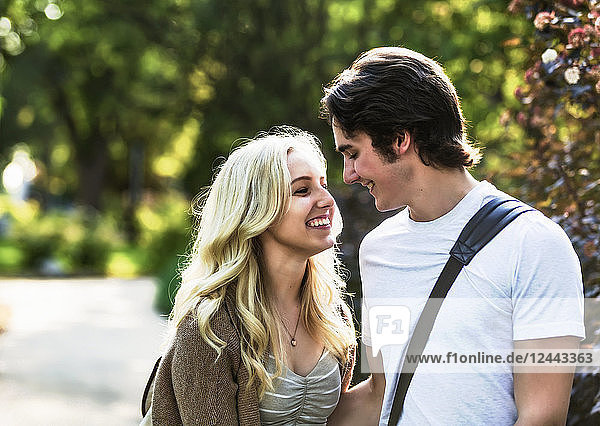 Ein junges Paar genießt einen romantischen Moment und denkt über einen Kuss nach  während es durch einen Universitätscampus geht  Edmonton  Alberta  Kanada