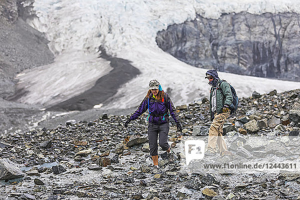 A husband and wife hike on the rugged surface of Gulkana Glacier  Alaska  United States of America