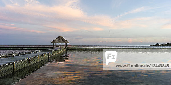 Eine Bank auf einem Steg mit Blick auf die Küste und den offenen Ozean bei Sonnenaufgang  Belize