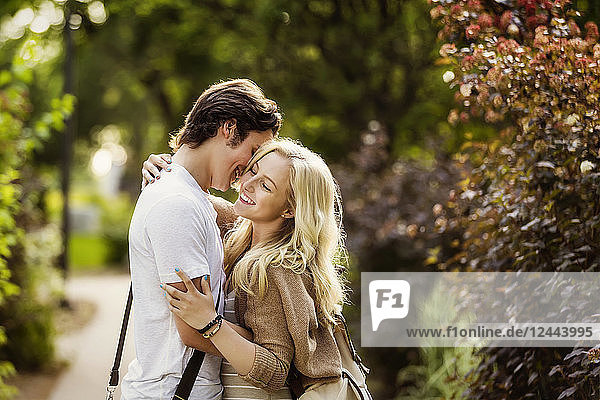 Ein junges Paar genießt einen romantischen Moment in einer Umarmung auf einem Weg auf dem Universitätscampus,  Edmonton,  Alberta,  Kanada