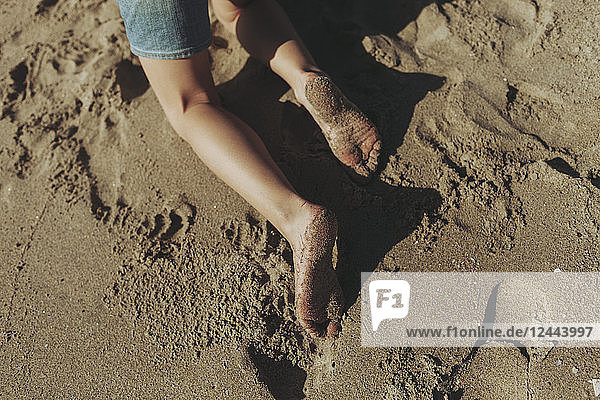 A child's wet feet covered in sand; Long Beach  California  United States of America
