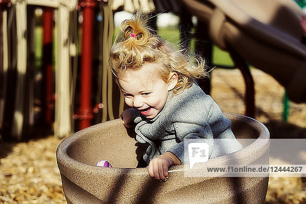 Ein niedliches junges Mädchen  das sich auf einem Spielplatz während der Herbstsaison in einer Untertasse dreht  Spruce Grove  Alberta  Kanada