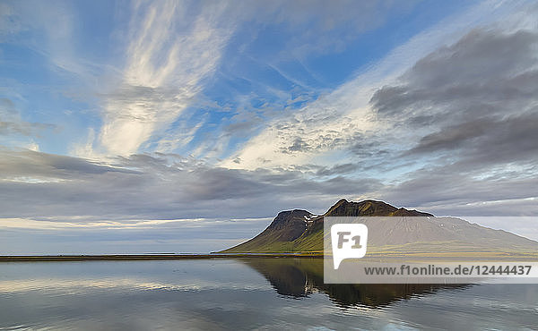 Die satte vulkanische Erde erzeugt kräftige Farben auf dem Berg vor dem sanften Blau des Ozeans und des Himmels in Westisland  Island