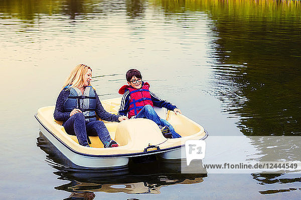 Mutter und Sohn fahren in einem Paddelboot auf einem See  halten sich an den Händen und sprechen miteinander; Edmonton  Alberta  Kanada