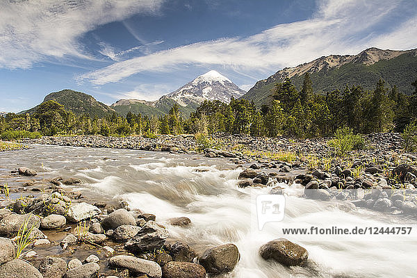 A mountain river with snow-capped volcano in the distance; Neuquen  Argentina
