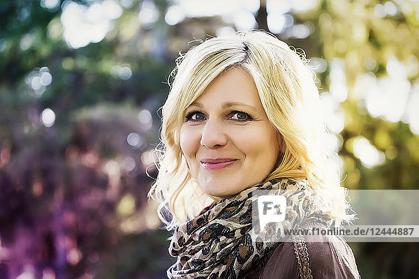 A beautiful blonde middle-aged woman poses for the camera while spending time in a park on a warm summer evening  St. Alberta  Alberta  Canada