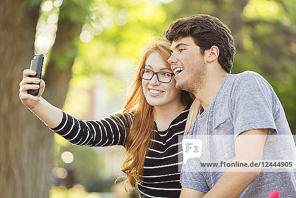 Ein junger Mann und eine junge Frau machen ein Selbstporträt mit einem Smartphone,  Edmonton,  Alberta,  Kanada