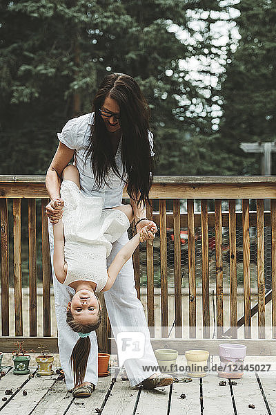 Portrait of a mother and young daughter playing together  the mother holding the daughter upside down; Alberta  Canada