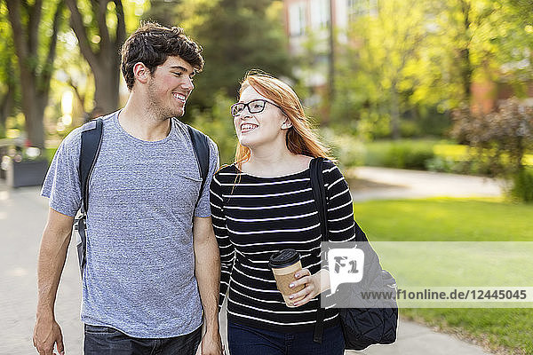 Ein junges Paar geht händchenhaltend durch einen Universitätscampus,  Edmonton,  Alberta,  Kanada