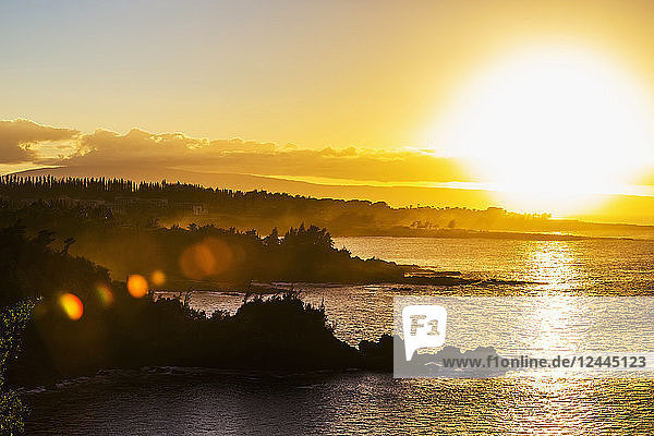 Ein goldener Sonnenuntergang  der gelbes Licht über den Ozean und die Küstenlinie in der Nähe der Honolua Bay  Kaanapali  Maui  Hawaii  Vereinigte Staaten von Amerika wirft