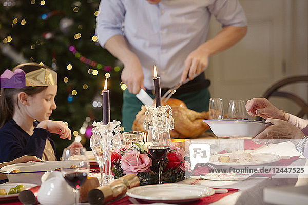 Vater tranchiert Weihnachtstruthahn bei Kerzenlicht am Tisch