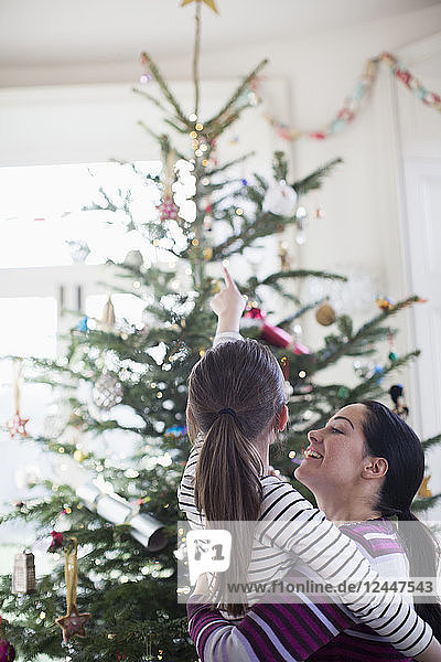 Liebevolle Mutter und Tochter mit Blick auf den Weihnachtsbaum