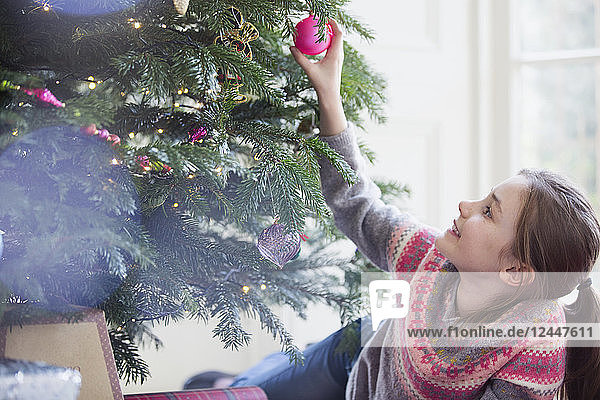 Neugieriges Mädchen berührt das Ornament am Weihnachtsbaum