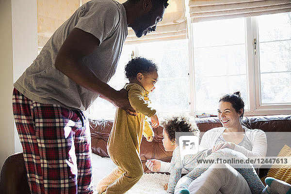 Verspielte multiethnische Familie im Pyjama im Wohnzimmer