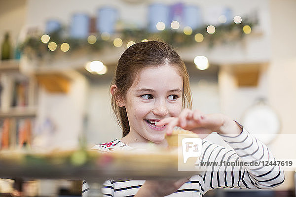 Lächelndes Mädchen isst Weihnachts-Cupcake