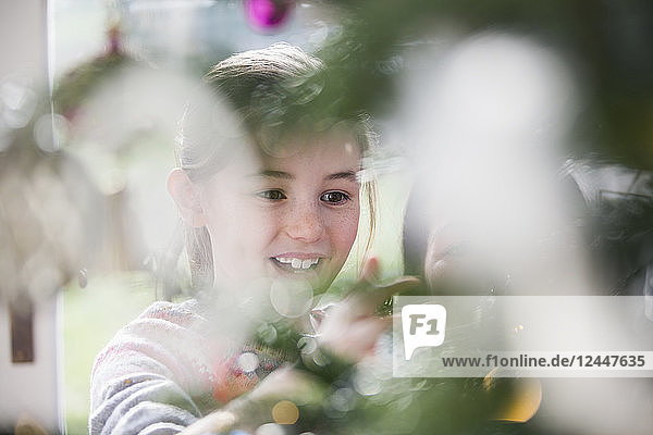 Lächelndes Mädchen beim Schmücken des Weihnachtsbaums
