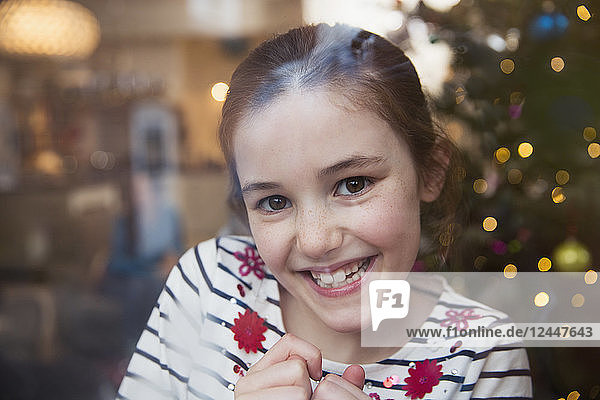 Porträt lächelndes  selbstbewusstes Mädchen im Weihnachtswohnzimmer