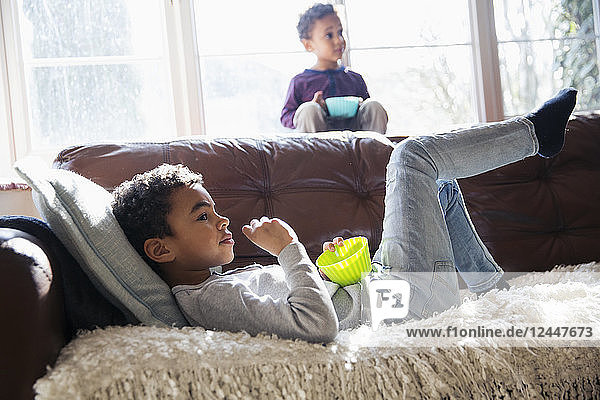 Brüder entspannen sich  sehen fern und genießen einen Snack auf dem Sofa im Wohnzimmer