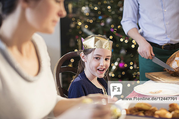 Smiling girl wearing paper crown at Christmas dinner