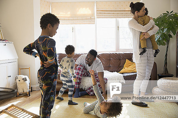 Multiethnische junge Familie im Schlafanzug spielt und entspannt sich im Wohnzimmer