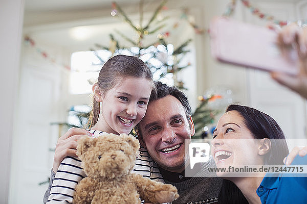 Glückliche Eltern und Tochter machen ein Selfie vor dem Weihnachtsbaum