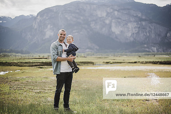 Portrait father and baby son standing in rural field