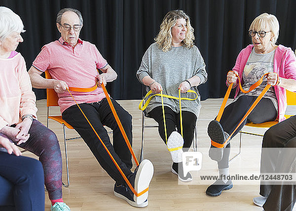 Active seniors exercising in circle  using straps to stretch legs