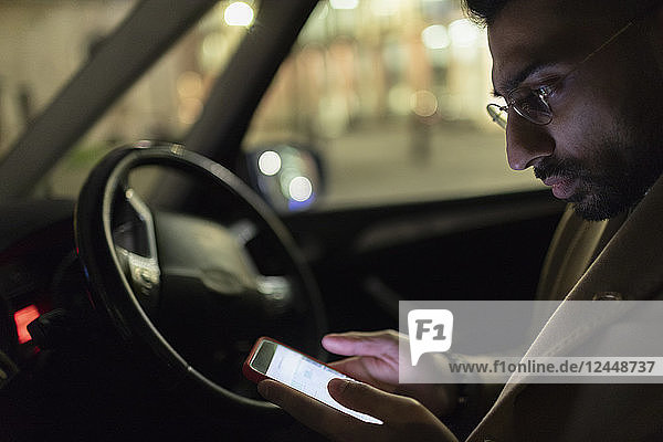 Man using smart phone in car at night