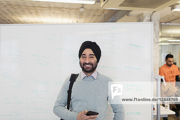 Portrait smiling  confident Indian businessman in turban standing at whiteboard in office
