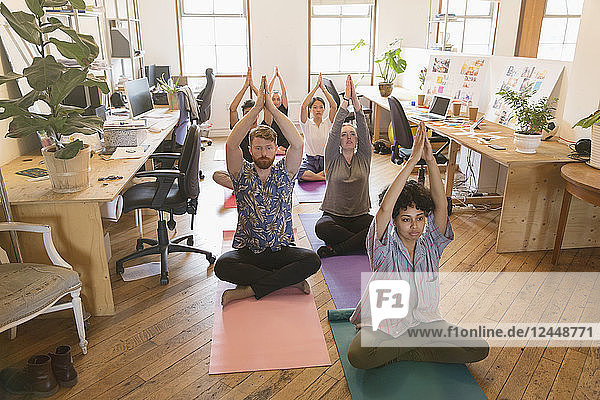 Creative business people practicing yoga in office