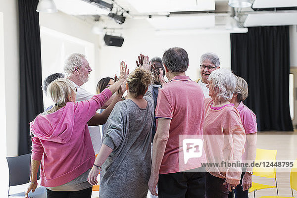 Active seniors high-fiving in circle huddle