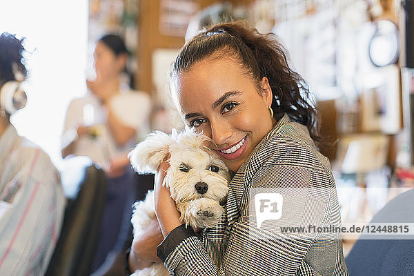 Portrait happy businesswoman with cute dog in office