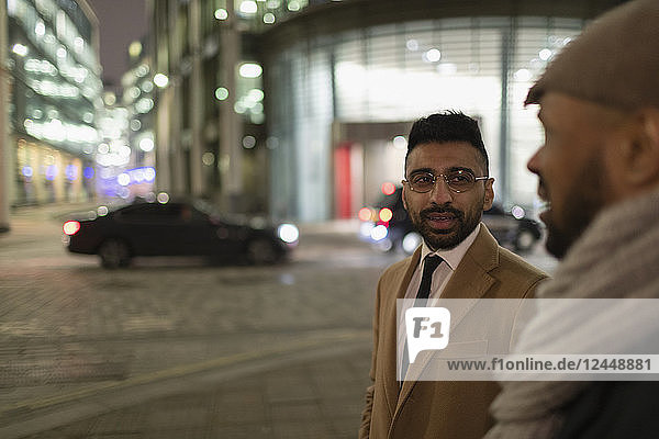 Businessmen talking on city street at night
