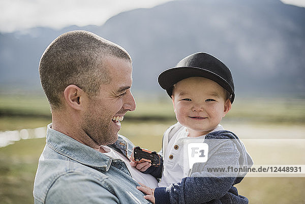 Father holding cute  happy baby son looking at camera