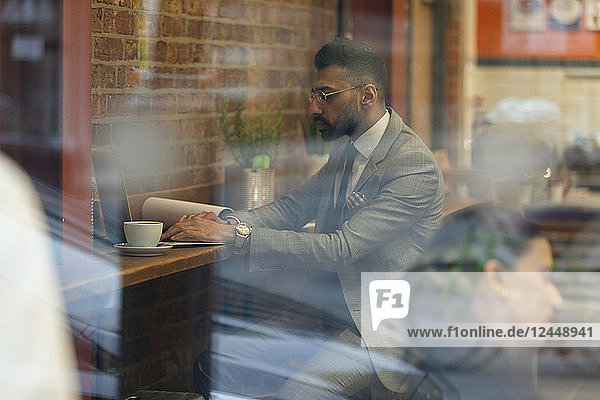 Businessman working at laptop in cafe