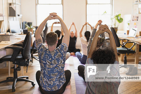 Creative business people practicing yoga in office
