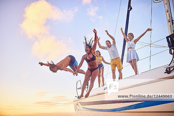 Playful friends jumping off boat