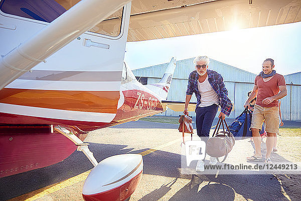 Men with bags boarding small airplane