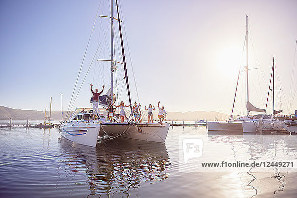 Portrait friends waving on catamaran in sunny harbor