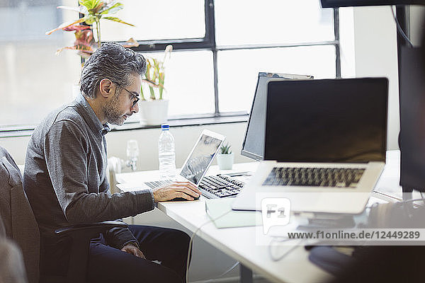Focused businessman working at laptop in office
