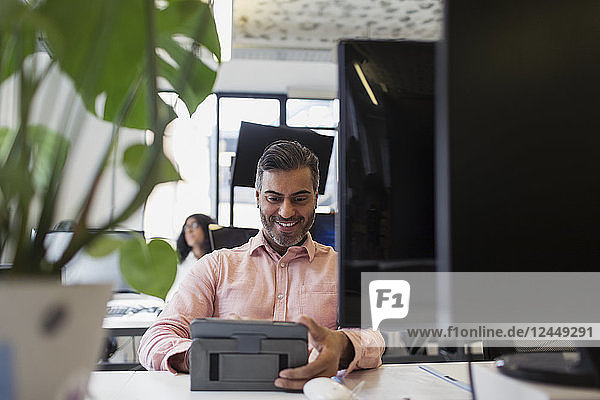 Smiling businessman using digital tablet in office