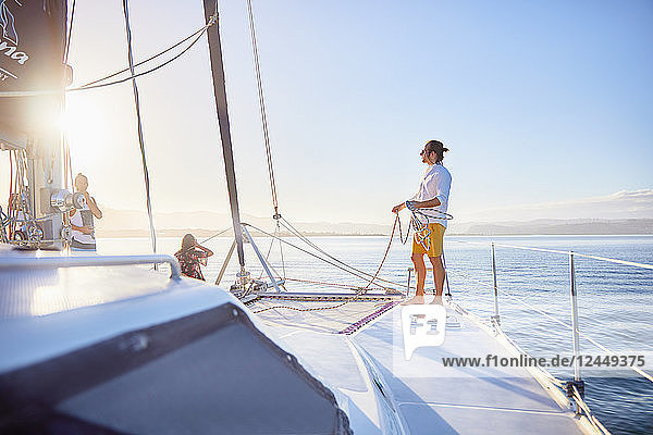 Young man holding rigging rope on sunny catamaran