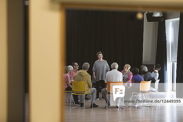 Woman leading seniors in group discussion in community center