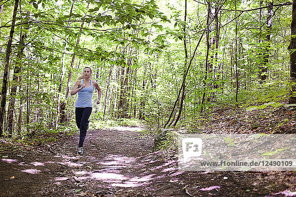 Fit young woman trail running on trails through woods at mount sabattus