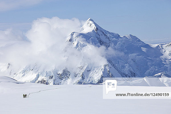 Zwei Bergsteiger überqueren einen Gletscher auf dem Mt. McKinley  Alaska. Im Hintergrund ist der Mount Hunter zu sehen. Der Mount McKinley (einheimischer Name Denali) ist der höchste Berg Nordamerikas mit einer Gipfelhöhe von 6.194 m über dem Meeresspiegel. Mit einer Höhe von rund 5.500 m (18.000 Fuß) ist der Anstieg von der Basis bis zum Gipfel der größte aller Berge  die sich vollständig über dem Meeresspiegel befinden. Gemessen an der topografischen Ausdehnung ist er nach dem Mount Everest und dem Aconcagua der drittgrößte Berg. Der McKinley befindet sich in der Alaska Range im Inneren des US-Bundesstaates Alaska und ist das Herzstück des Denali National Park and Preserve.