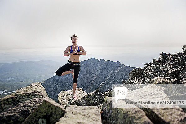 A young woman practices yoga at the summit of Mount Katahdin  Maine.