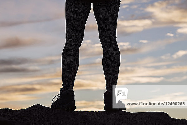 Silhouette der Beine eines weiblichen Wanderers bei Sonnenuntergang