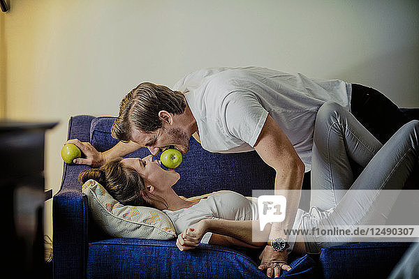 Ein süßes junges Paar isst Apfel auf einem Sofa in einem Hotelzimmer in Dallas
